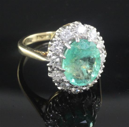 An 18ct gold, emerald and diamond oval cluster ring, size L.